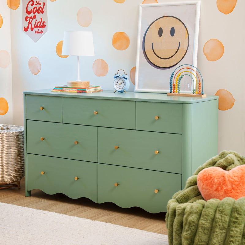 Green kids dresser styled with white lamp, blue alarm clock, wooden bead abacus and framed smiley art on orange polka-dot nursery wall