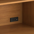 Close-up of wood cabinet shelf interior with recessed black power outlet featuring two AC sockets and dual USB charging ports