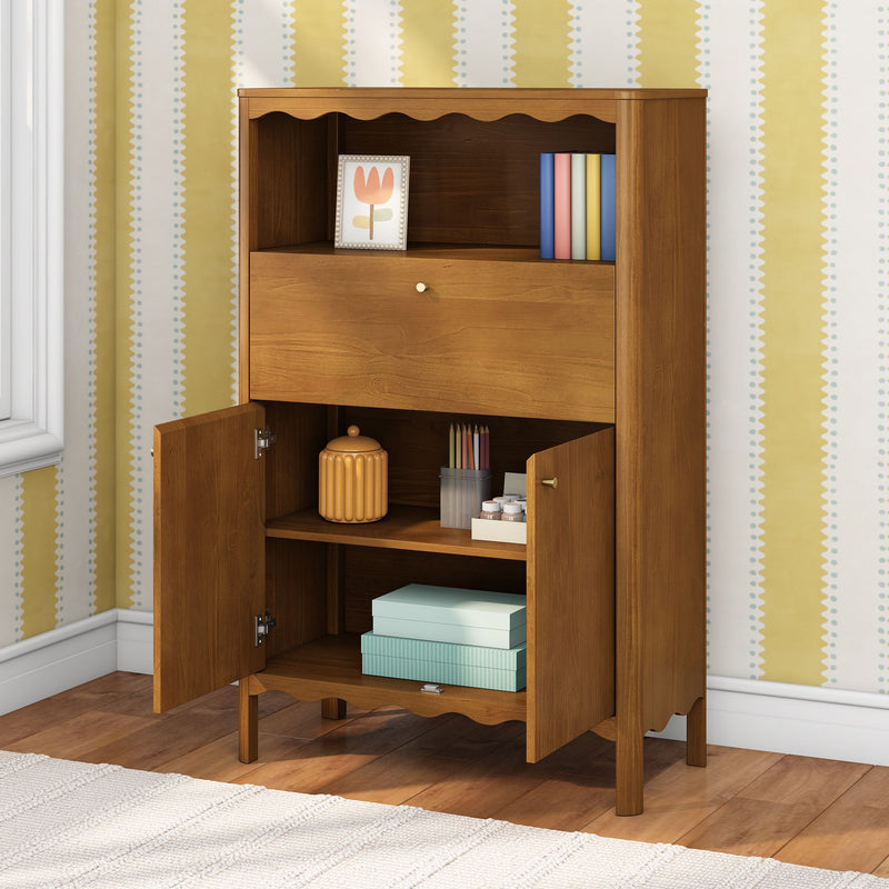 Wooden storage cabinet with open doors and shelves holding a decorative jar, colored pencils, stacked teal gift boxes and a framed tulip print against yellow patterned nursery wallpaper on hardwood floor
