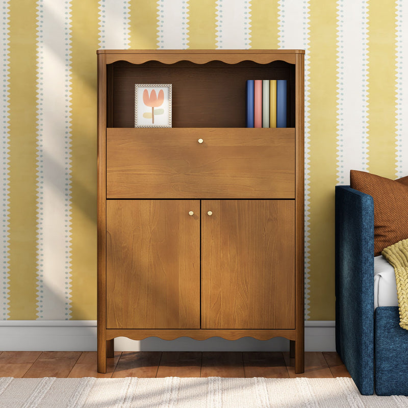 Wooden bedroom cabinet with scalloped trim against yellow patterned wallpaper, framed tulip artwork, colorful books and blue upholstered bed