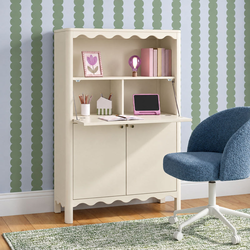 Children's scalloped cream desk with drop-front hutch, pink accent lamp and books, green scalloped-stripe wallpaper and blue swivel chair