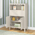 Beige wooden nursery storage cabinet with scalloped trim, open shelves holding pastel books, art frame and storage boxes against green scallop wallpaper