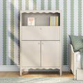 Cream nursery changing cabinet with scalloped trim, green scalloped wallpaper, framed tulip art and pastel books