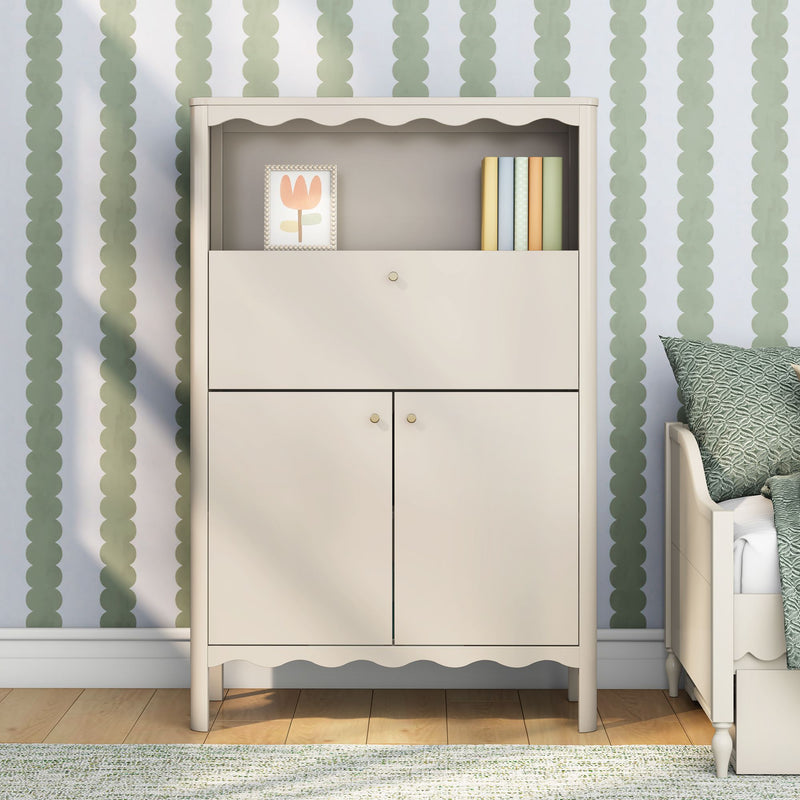 Cream nursery changing cabinet with scalloped trim, green scalloped wallpaper, framed tulip art and pastel books