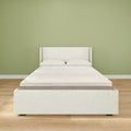 Minimalist modern bedroom interior with white upholstered bed frame, mattress and two pillows on light hardwood floor against a sage green accent wall