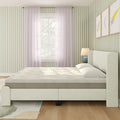 Minimal modern upholstered bed with neutral mattress in a sunlit bedroom featuring green striped wallpaper, sheer curtains, wooden nightstand and lamp