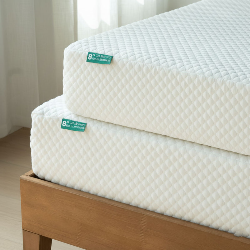 Close-up of stacked 8-inch gel memory foam mattresses with white quilted cover on a wooden bed frame