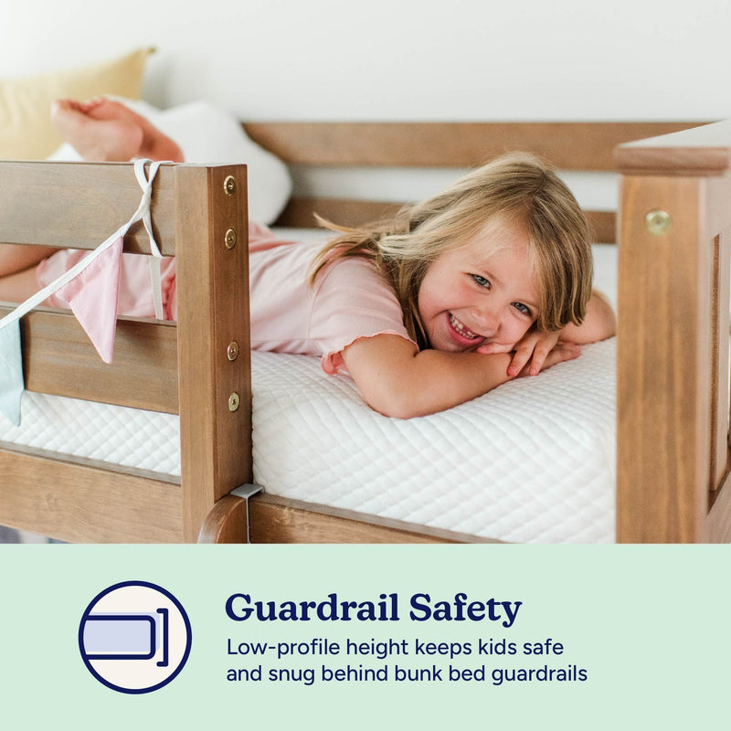 Smiling child on mattress behind low-profile wooden bunk bed guardrail — safety-focused bunk bed guardrails for kids