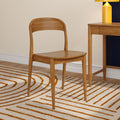 Scandinavian natural wood chair beside matching wooden desk on beige wall, orange-striped rug and yellow table lamp — modern minimalist interior