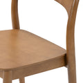 Close-up of light solid wood dining chair seat and curved backrest showing natural wood grain and mid-century modern design