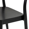 Close-up of black wooden dining chair seat and rounded legs, modern matte-finish kitchen chair detail