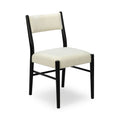 Close-up of cream boucle upholstered dining chair with padded seat and back and black wooden frame, modern minimalist design