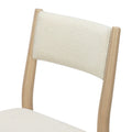 Close-up of cream boucle upholstered dining chair back with light natural wood frame, modern Scandinavian-style dining chair