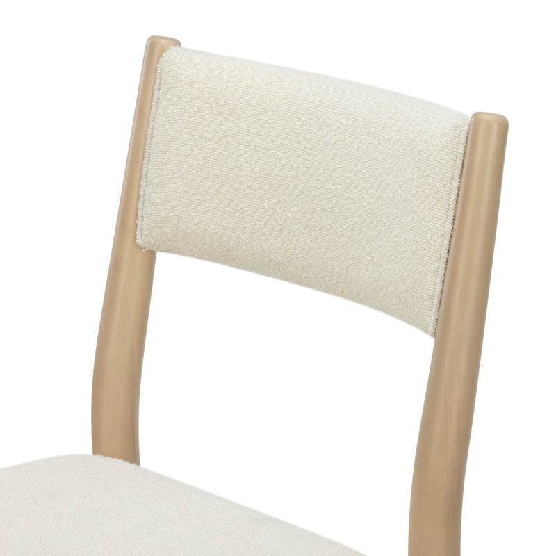 Close-up of cream boucle upholstered dining chair back with light natural wood frame, modern Scandinavian-style dining chair