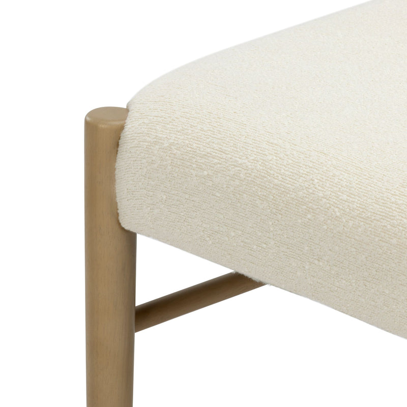 Close-up of cream boucle upholstered ottoman seat showing textured boucle fabric and rounded natural wood legs
