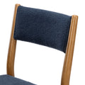 Close-up of navy boucle upholstered backrest on a mid-century modern walnut dining chair, showing textured fabric and wooden frame