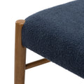 Close-up of navy blue textured upholstery on a round seat with walnut-toned wooden chair leg, modern stool detail