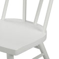 Close-up of white painted wooden spindle-back dining chair seat and legs with matte finish, modern farmhouse style