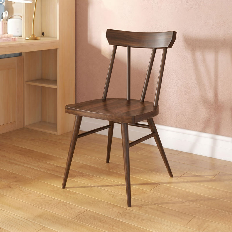 Dark walnut wooden chair beside a light wood desk against a pink textured wall on oak hardwood floor — minimalist Scandinavian interior.