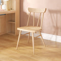 Light oak wooden chair by oak desk with brass lamp on pink textured wall in minimalist home office with hardwood floor