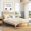 Coastal kids bedroom with natural wood bed, yellow striped bedding, rattan lamp, surf-van wall art and ocean-view window