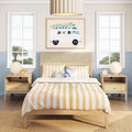 Beach-themed kids bedroom with striped beige bedding, natural rattan headboard, surfboard-van wall art, wooden nightstands and palm-tree window view