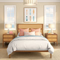 Coastal bedroom interior with rattan headboard, pastel pillows, surfboard wall art, bedside lamps and ocean-view windows