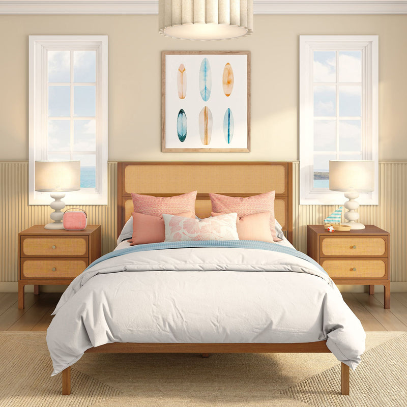Coastal bedroom interior with rattan headboard, pastel pillows, surfboard wall art, bedside lamps and ocean-view windows