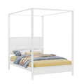 White four-poster canopy bed with paneled headboard and layered blue, yellow, and beige bedding — modern minimalist bedroom furniture