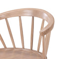 Close-up of curved spindle-back wooden dining chair with smooth natural light wood finish and rounded armrest, Scandinavian modern style