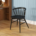 Black wooden spindle-back chair in a modern home office with light blue vertical paneled wall, walnut desk, task lamp and oak hardwood floor