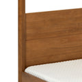 Close-up of honey oak solid wood bed headboard and frame with white quilted mattress cover