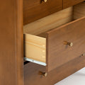 Open solid wood dresser drawer showing dovetail joinery, brass knobs, metal drawer slides and warm brown finish
