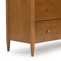 Close-up of mid-century modern solid wood dresser with warm walnut finish, tapered legs and round brass knobs on two drawers