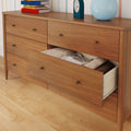 Mid-century modern wooden 6-drawer dresser with one open drawer showing folded linens on a hardwood floor, styled with stacked books, a blue vase and clock — bedroom storage furniture