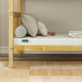 5-inch gel memory foam mattress on light wooden twin bed frame with textured cream pillows, bolster and folded white sheets in a minimalist beige bedroom