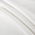 Close-up of white breathable waffle-weave fabric with soft texture and subtle honeycomb pattern, ideal for bedding, sheets, and mattress protectors