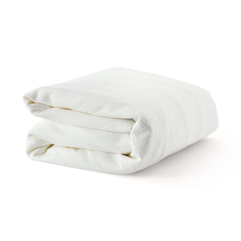 Folded white waffle-knit cotton blanket on white background, breathable textured throw for bed or sofa
