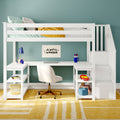 White wooden loft bed with built-in study desk in teal kids' bedroom, striped pillows and yellow blanket, laptop, lamp, toys and storage stairs