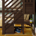 Wooden loft bed stairs with built-in cubby storage and diagonal railing, showing a potted succulent, folded pillows, blue sneakers and yellow wire basket on a mustard rug