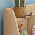 Close-up of wooden toy shelf in a kids' nursery with a smiling woven plant pot, pastel stacking rings and wooden toys against a blue wall