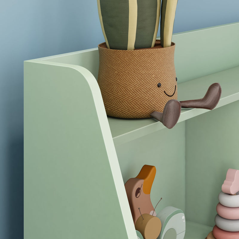 Pastel green nursery shelf with a smiling woven storage basket, fabric plant, wooden animal toys and pastel stacking rings