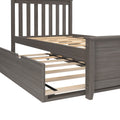 Gray wood platform bed frame with vertical slatted headboard, exposed wooden slats and pull-out trundle on casters, modern farmhouse style